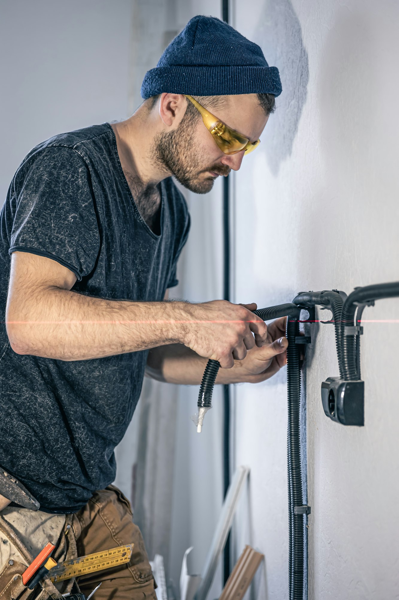 An electrician is mounting electric sockets on the white wall indoors.