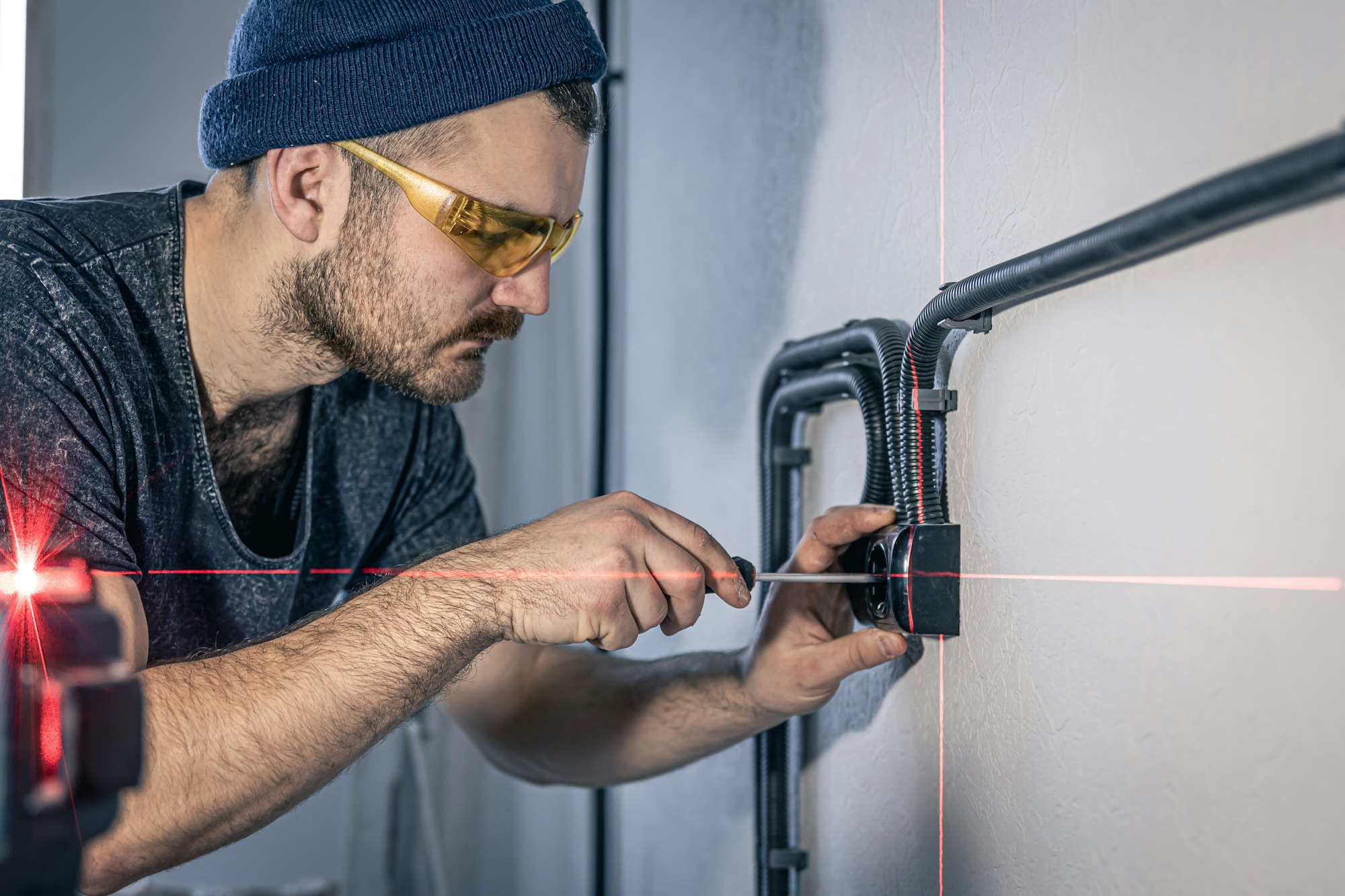 An electrician is mounting electric sockets on the white wall indoors.