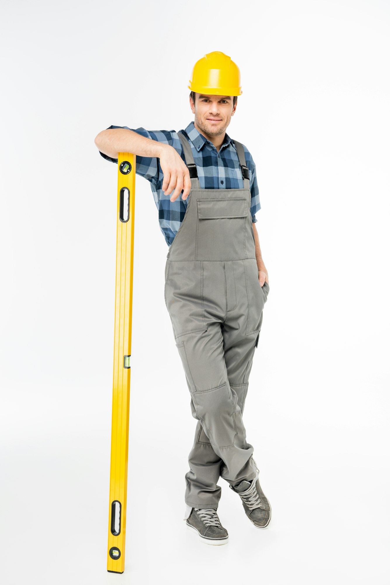 Full length portrait of workman with level tool smiling at camera isolated on white