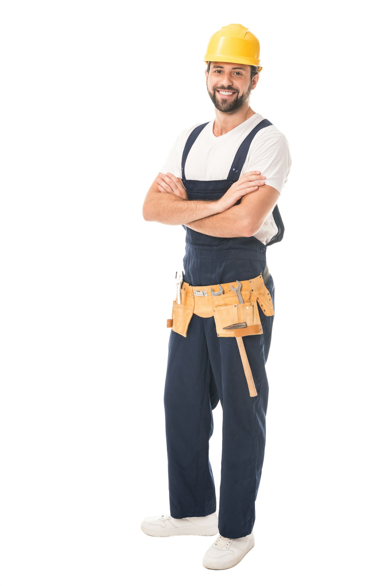 full length view of handsome happy workman in hard hat and tool belt standing with crossed arms and