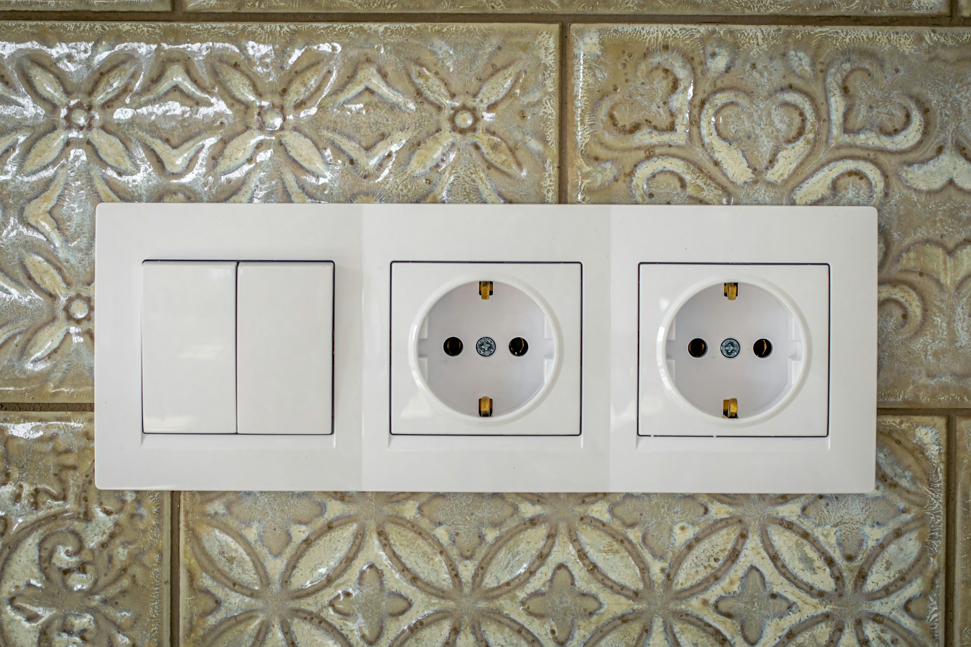 White plastic walk-through switches and sockets on a white wall.